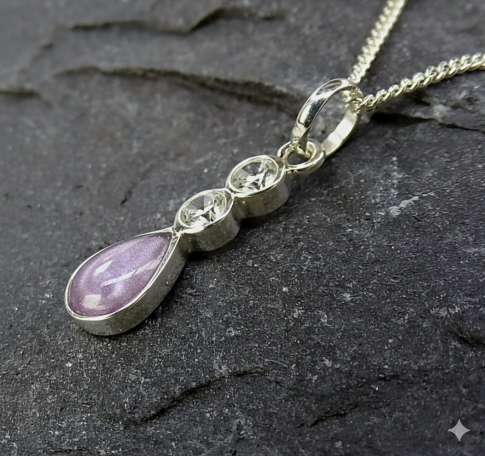 Silver necklace with a pink teardrop pendant and two clear stones above it.
